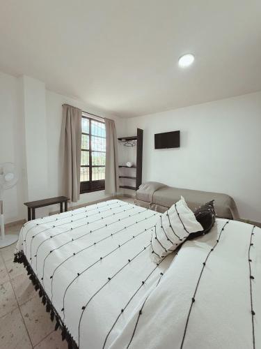 a large white bed in a room with a couch at Casa Monarca in Oaxaca City