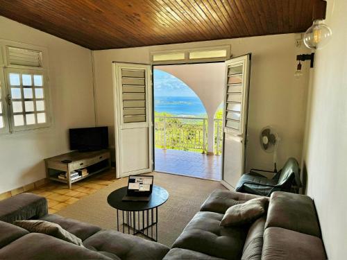 a living room with a couch and an open door at Terrasse Panoramique, Calme et Spacieux, Vue sur Mer in Le Lamentin