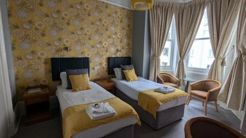 a hotel room with two beds and a window at Alexandra Hotel in Eastbourne