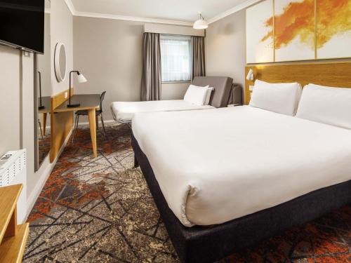 a hotel room with two beds and a desk at ibis Styles Birmingham Centre in Birmingham