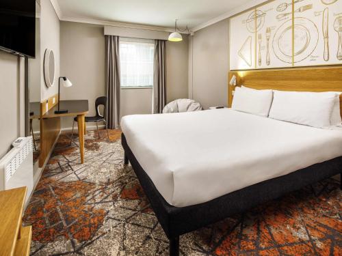a hotel room with a large bed and a desk at ibis Styles Birmingham Centre in Birmingham