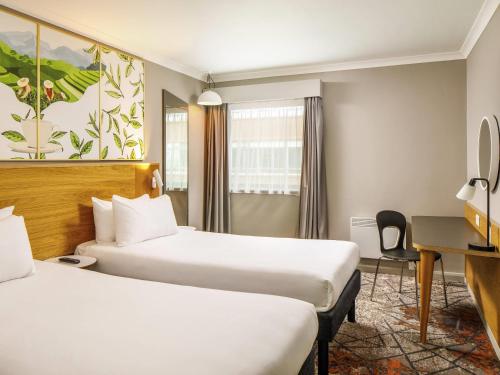 a hotel room with two beds and a desk at ibis Styles Birmingham Centre in Birmingham