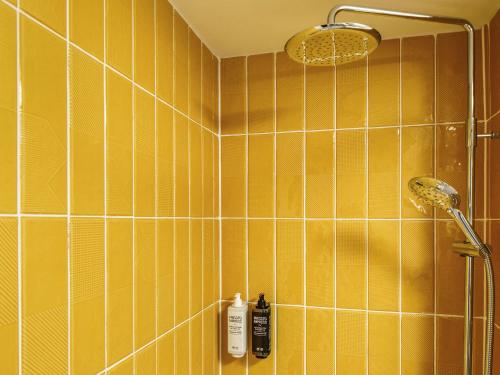 a bathroom with a shower with yellow tiles at ibis Styles Birmingham Centre in Birmingham