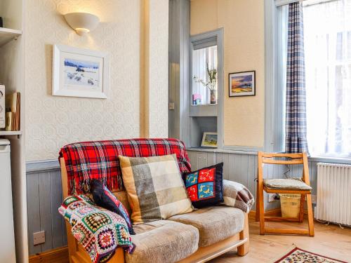 a living room with a couch with pillows on it at Kirk Wynd Cottage in Kirriemuir