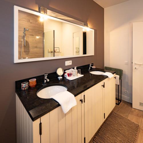 a bathroom with two sinks and a large mirror at De Moeraseik in Zele