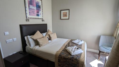 a small bedroom with a bed and a chair at Alexandra Hotel in Eastbourne
