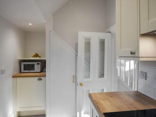 Una cocina con gabinetes blancos y una puerta blanca. en Tŷ Clara, en Llangollen