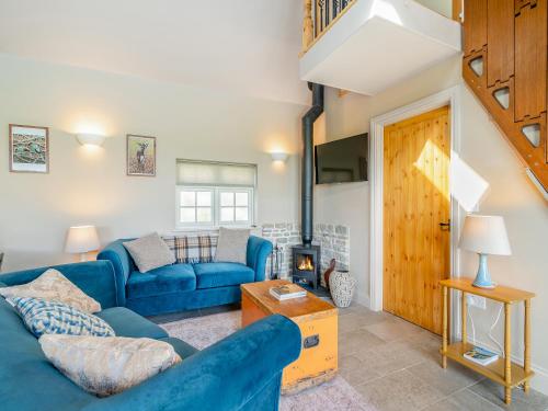 a living room with a blue couch and a fireplace at Stone Cottage in Wedmore