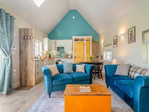 a living room with blue couches and a kitchen at Stone Cottage in Wedmore