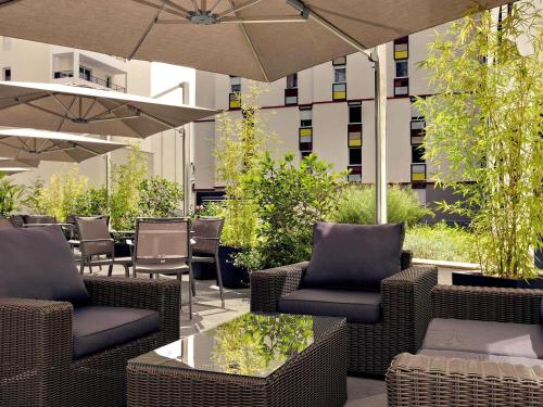 a patio with chairs and tables and an umbrella at Mercure Clermont Ferrand centre Jaude in Clermont-Ferrand