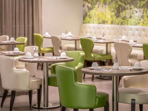 a dining room with tables and green chairs at Mercure Clermont Ferrand centre Jaude in Clermont-Ferrand