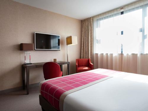 a hotel room with a bed and a desk and a tv at Mercure Clermont Ferrand centre Jaude in Clermont-Ferrand