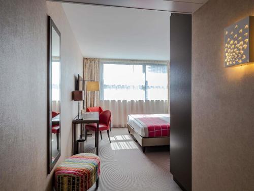a hotel room with a bedroom with a bed and a desk at Mercure Clermont Ferrand centre Jaude in Clermont-Ferrand