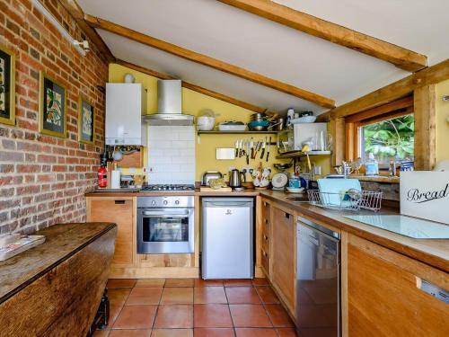 a kitchen with wooden cabinets and a brick wall at The Old Bike Shop in Brockdish
