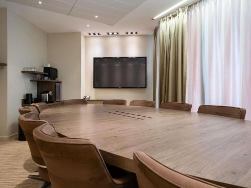 a conference room with a large wooden table and chairs at Mercure Clermont Ferrand centre Jaude in Clermont-Ferrand