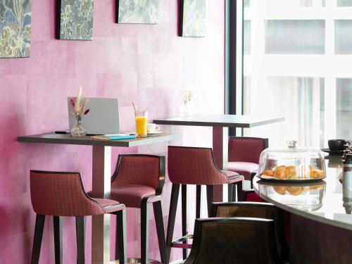 a restaurant with pink walls and tables and chairs at Mercure Clermont Ferrand centre Jaude in Clermont-Ferrand