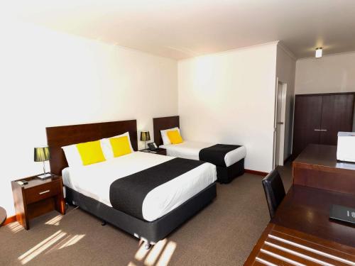 a hotel room with two beds and a desk at Mercure Port of Echuca in Echuca