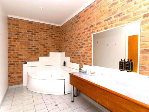 a bathroom with a large mirror and a tub at Mercure Port of Echuca in Echuca