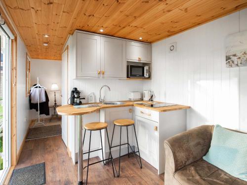 una cucina con mobili bianchi e un bancone con sgabelli di School Lodge a Burwarton