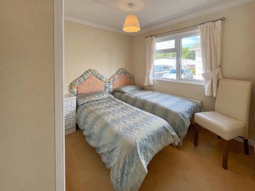 a bedroom with two beds and a chair and a window at Tredegar in Newton Stewart
