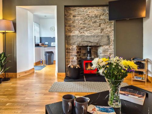 a living room with a stone fireplace and a table with flowers at Lena's Corner in Dunoon