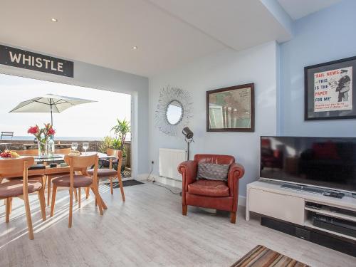 a living room with a dining table and a television at Seaspray, Coastguard Cottages in Dawlish