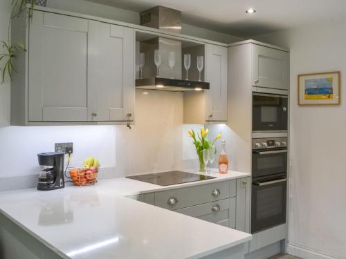 a kitchen with white cabinets and a white counter top at Humford Mill Cottage in Bedlington