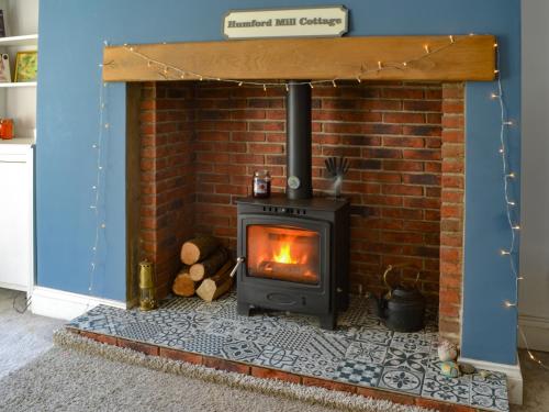 a brick fireplace with a stove in a room at Humford Mill Cottage in Bedlington