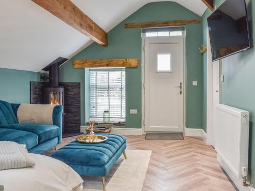 a living room with green walls and a blue couch at Barn Owls Nest-Uk39432 in Dronfield