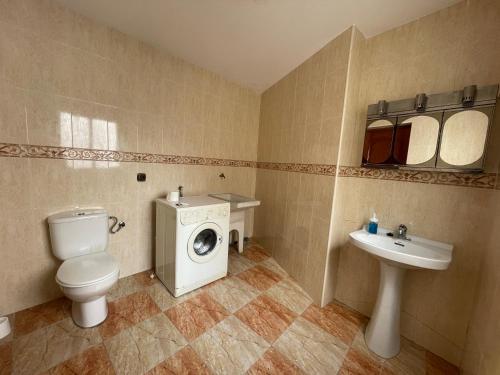 a bathroom with a toilet a sink and a washing machine at La casita del pueblo in Molvízar