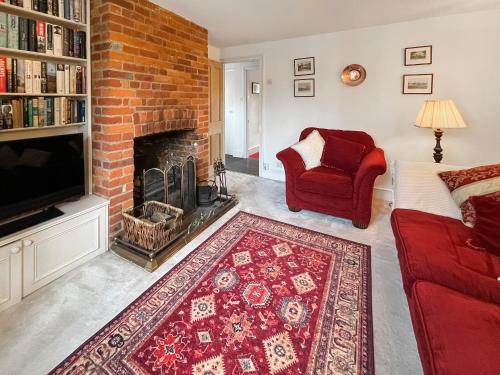 a living room with a brick fireplace and a red couch at Green Trees in Maidstone