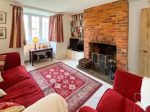 a living room with a red couch and a brick fireplace at Green Trees in Maidstone