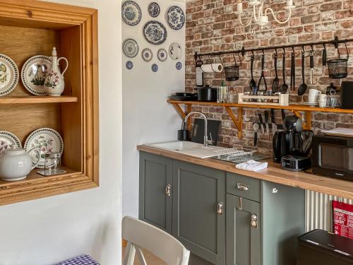 a kitchen with green cabinets and a brick wall at Tanglemere in Badsey