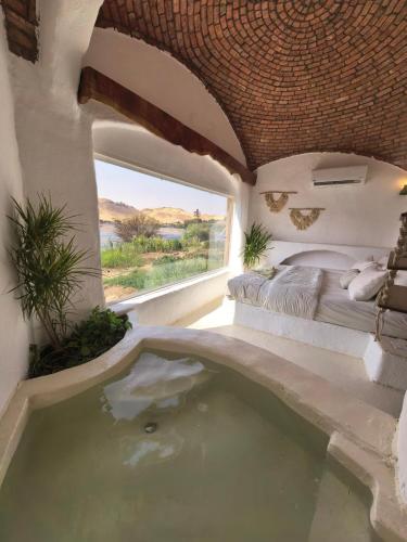 a room with a tub with a bed and a window at Nala Narty Boutique Hotel & Farm in Aswan