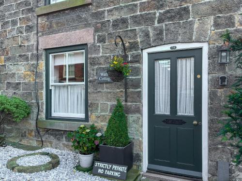 a brick house with a green door and a window at Wattle Cottage in Belper