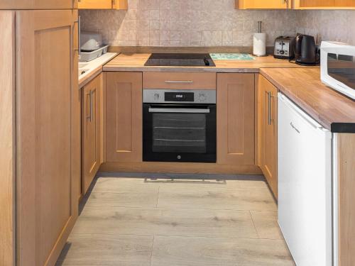 a kitchen with wooden cabinets and an oven at Bonnieville in Hunstanton