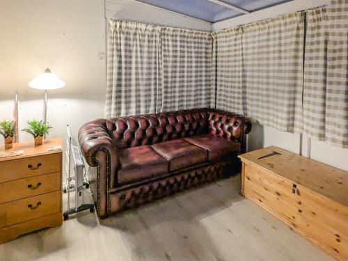a brown leather couch in a living room with a table at Bonnieville in Hunstanton