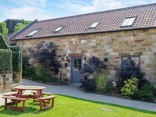 a stone house with two picnic tables in front of it at St Hildas Rest in Hinderwell