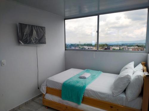 a small bedroom with a bed and a window at Hostel viajeros in Armenia