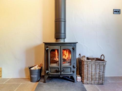 a stove with a fire in a room with a basket at Queens Barn in Wortham