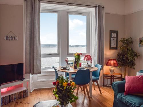 a living room with a table and a large window at The Seaside Suite in Helensburgh