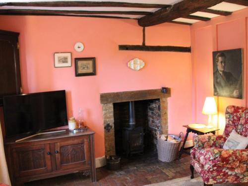 un salon avec une télévision et une cheminée dans l'établissement Lavender Cottage, à Methwold