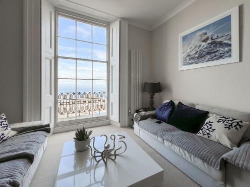 Una sala de estar con un sofá y una mesa y una ventana. en Admiral's Lookout, en Ilfracombe