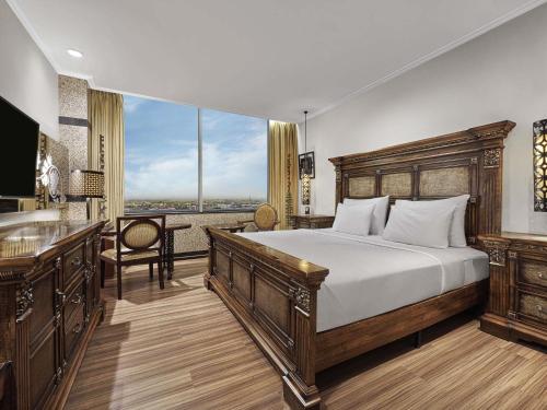 a bedroom with a bed and a desk and a window at The Royal Surakarta Heritage - Handwritten Collection in Solo