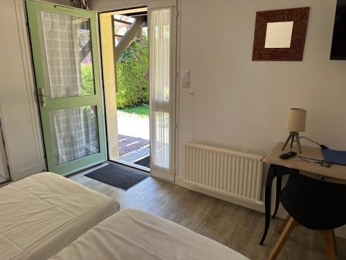 a bedroom with a bed and a sliding glass door at Logis Hôtel La Demeure du Perron in Quettehou