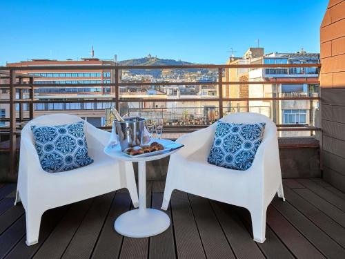 a balcony with two chairs and a table with food on it at Mercure Barcelona Condor in Barcelona