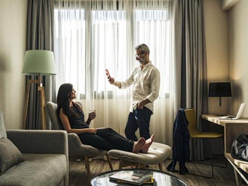 a man standing next to a woman in a living room at Mercure Barcelona Condor in Barcelona