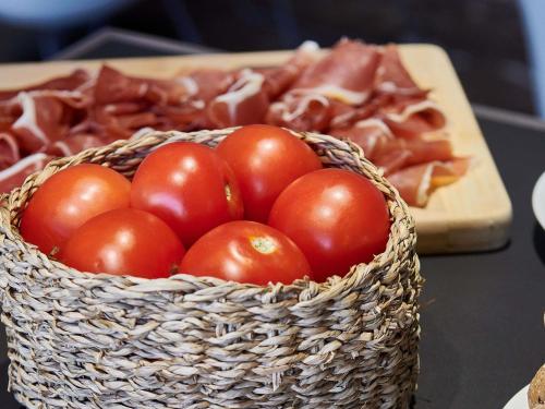 a basket of tomatoes and ham on a table at Mercure Barcelona Condor in Barcelona
