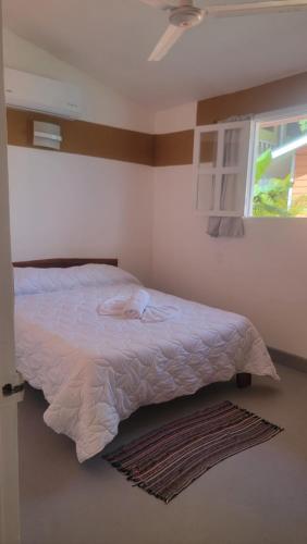 a bedroom with a white bed with a window and a rug at Residencial Oasis in Sámara