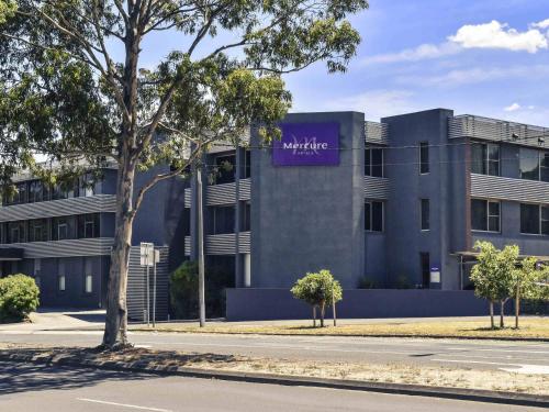 a building with a purple sign on the side of it at Mercure North Melbourne in Melbourne